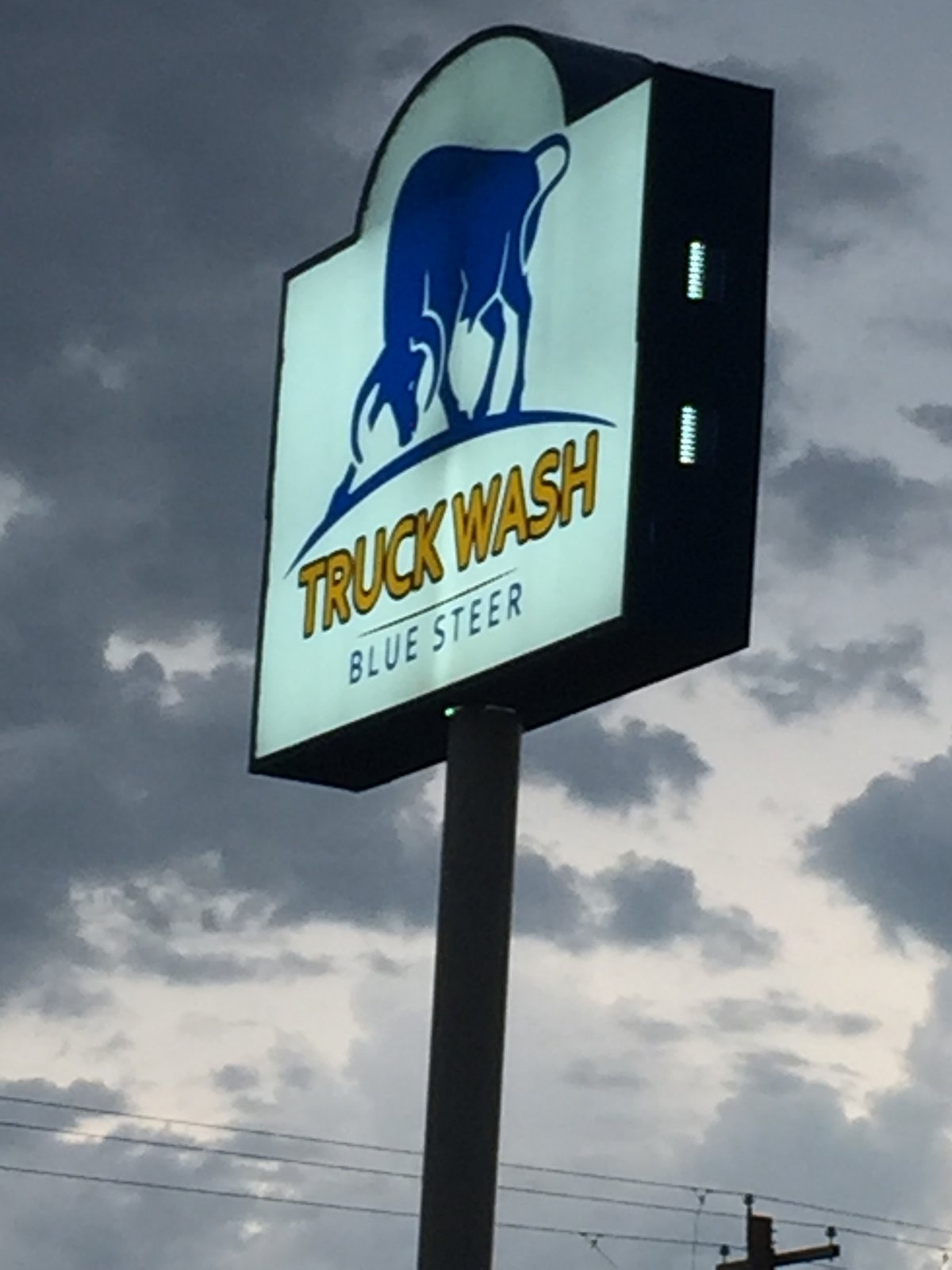 Blue Steer pole sign against a dramatic Texas sky